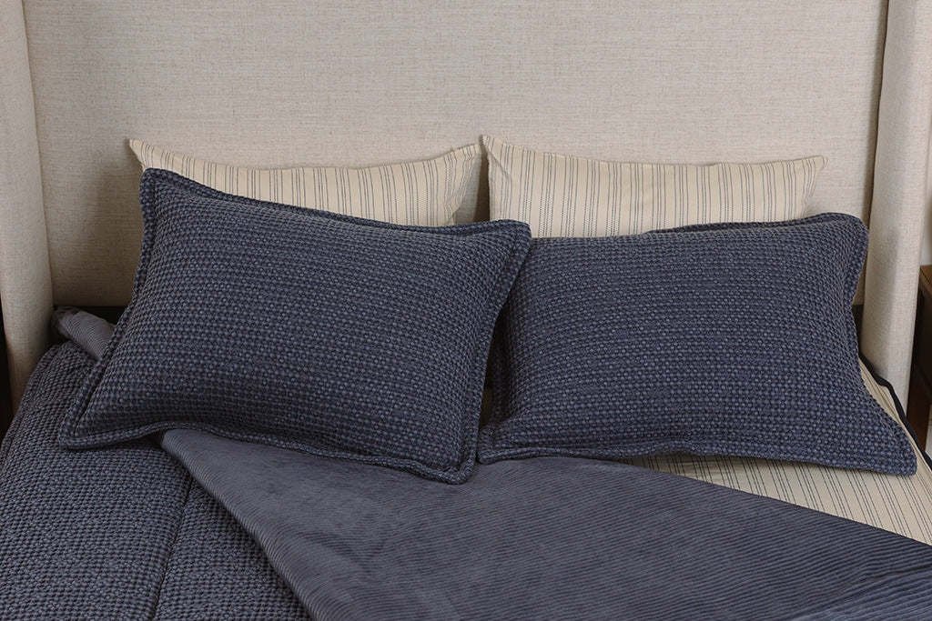 Overhead photo of blue waffle texture zipper bedding with cream and blue striped bed sheets and blue corduroy minky interior.