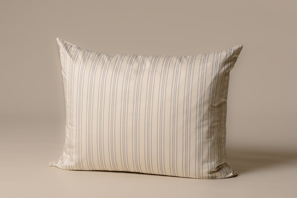 A cream and blue striped pillowcase on an cream backdrop.