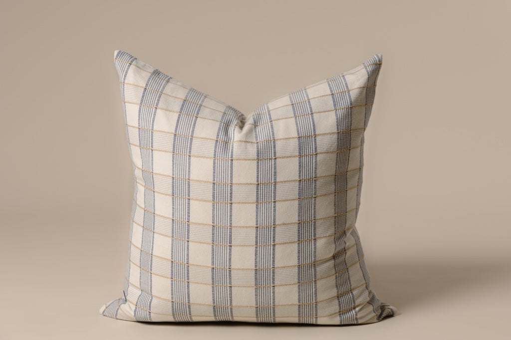Yellow and blue plaid pillow on a tan backdrop.