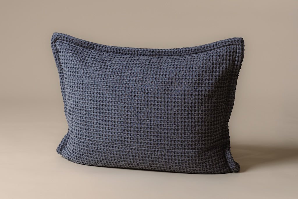 A blue waffle textured sham on a cream backdrop.