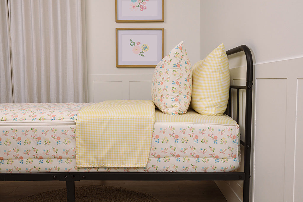 A bed made with gingham and floral printed zipper bedding, showcasing the pillowcase and sham and the top of the bedding turned down to show the inside lining.