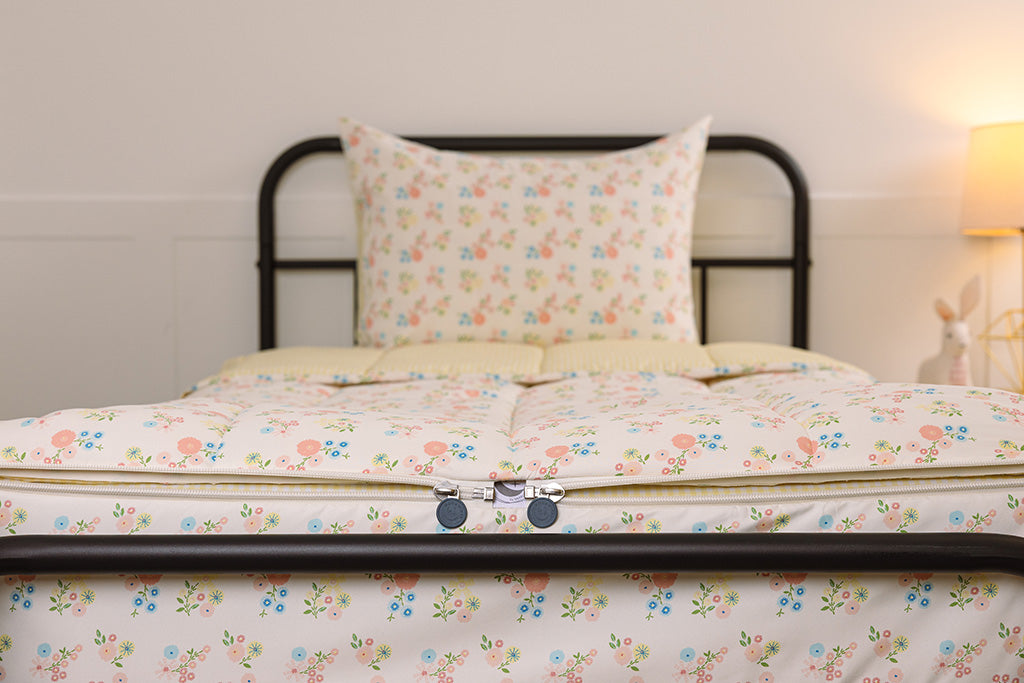 A shot of the two zippers on a set of flower printed zipper bedding, the zippers completely unzipped to show how they meet at the foot of the bed.
