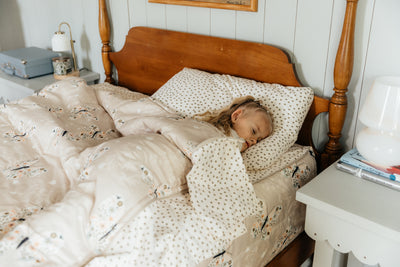 A young girl asleep in a full size bed four poster bed made with butterfly zipper bedding.
