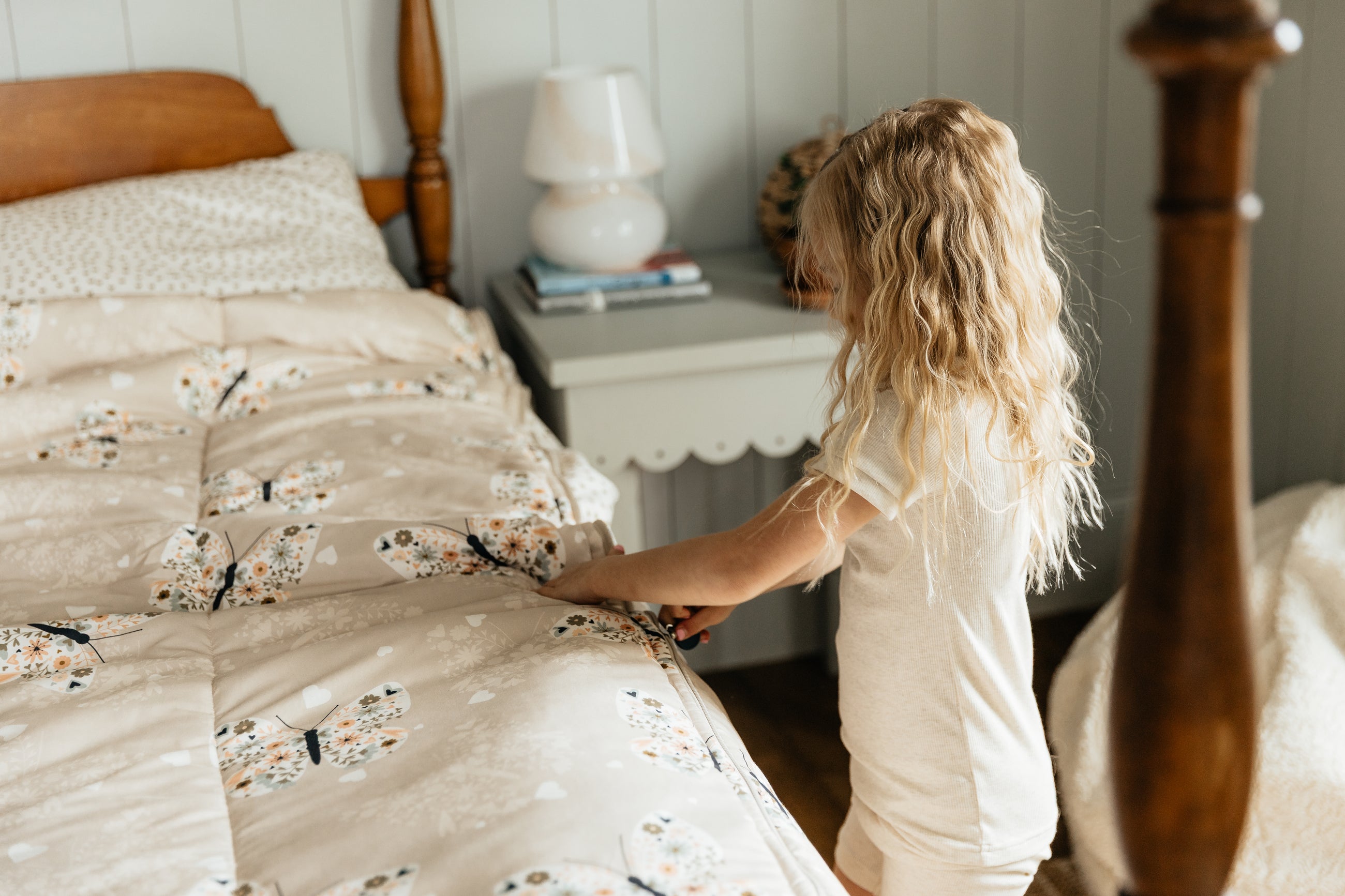 A young girl pulling the zipper shut on a set of butterfly zipper bedding.