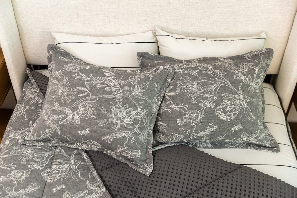 Overhead photo of sketched floral zipper bedding with gray striped bed sheets and gray minky interior.