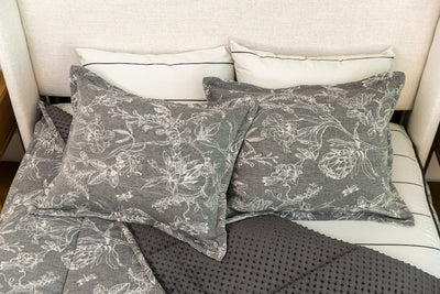 Overhead photo of sketched floral zipper bedding with gray striped bed sheets and gray minky interior.