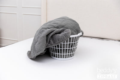 The ZipBase sheet and top comforter portion removed and sitting in a basket on top of a bed
