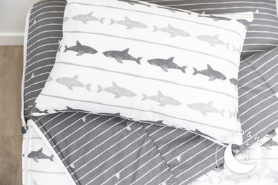 A twin bed made with shark kids zipper bedding, the top unzipped and pulled slightly back and a pillow on top