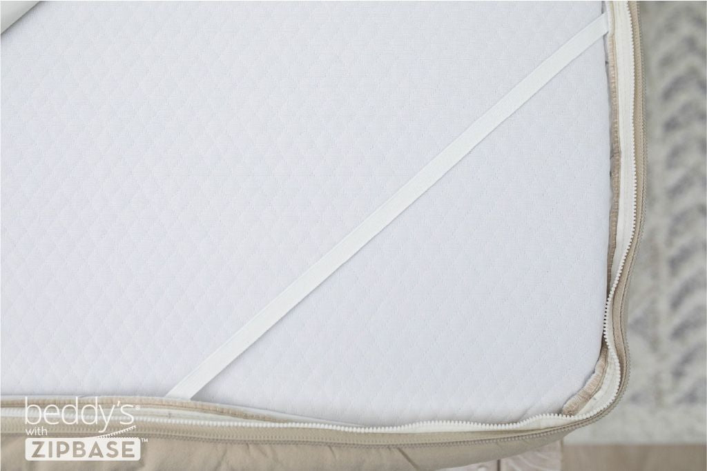 A close up on the elastic strap that runs across each corner of a mattress when there is a Beddy's ZIpBase zipper bedding set on it