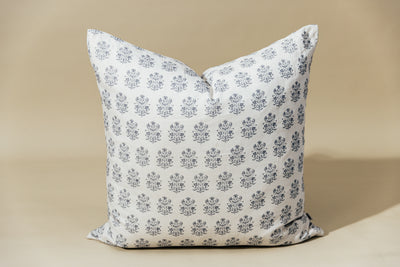 A white euro pillow with a blue floral design arranged on a tan background.