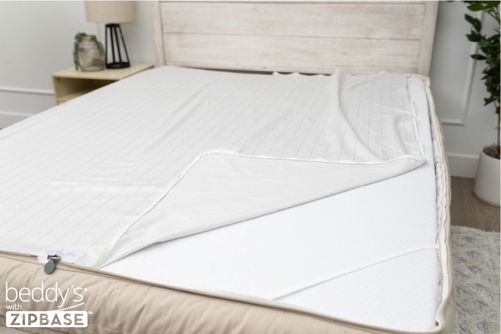A ZipBase sheet partially unzipped and pulled back to show how it detaches from the rest of the base sheet wrapped around the sides of the mattress.