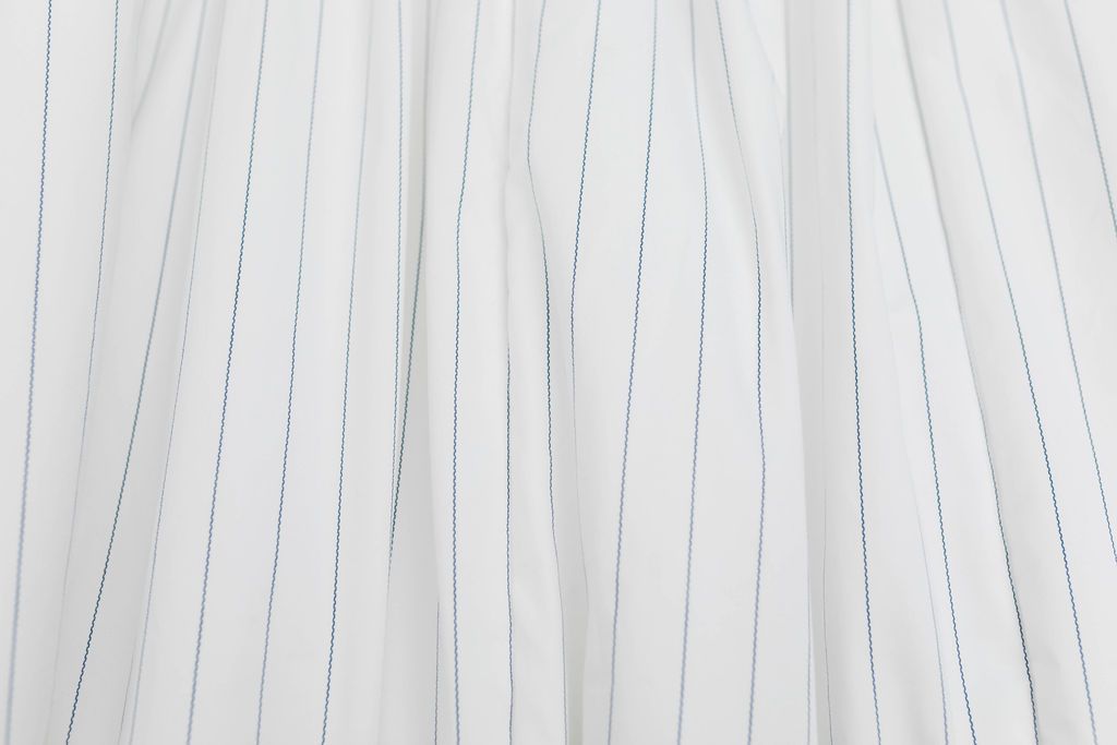 A close up of a white and light thin blue striped blanket.