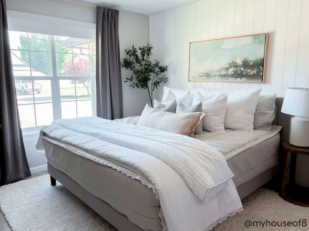 A queen bed made with light gray waffle textured zipper bedding and an assortment of neutral and striped throw pillows and blankets.