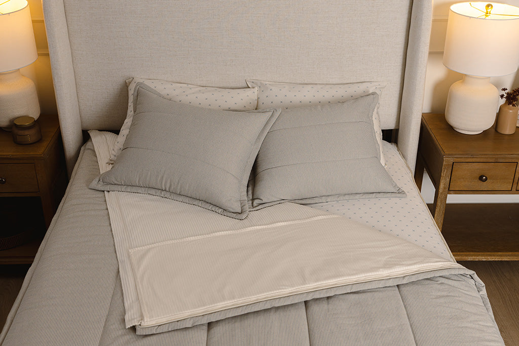 Overhead photo of blue striped zipper bedding with cream and blue crossed bed sheets and cream cordroy minky interior.