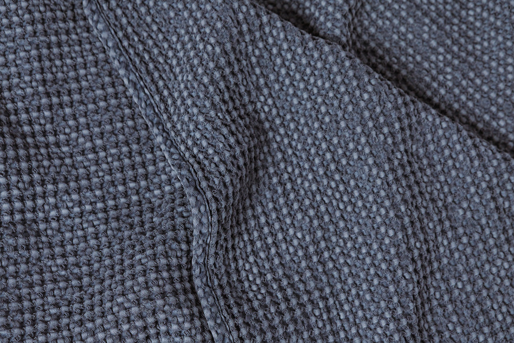 A photo that shows the dusty blue waffle weave color and texture of throw blanket.
