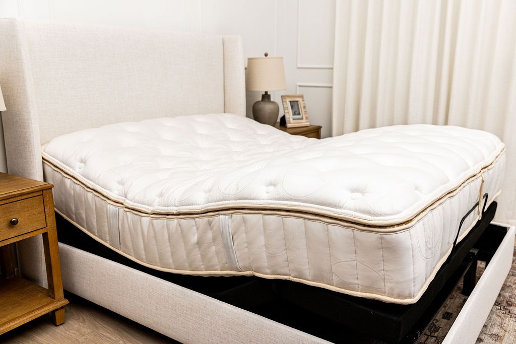 A mattress on top of an adjustable base with the head and foot of the bed slightly raised.