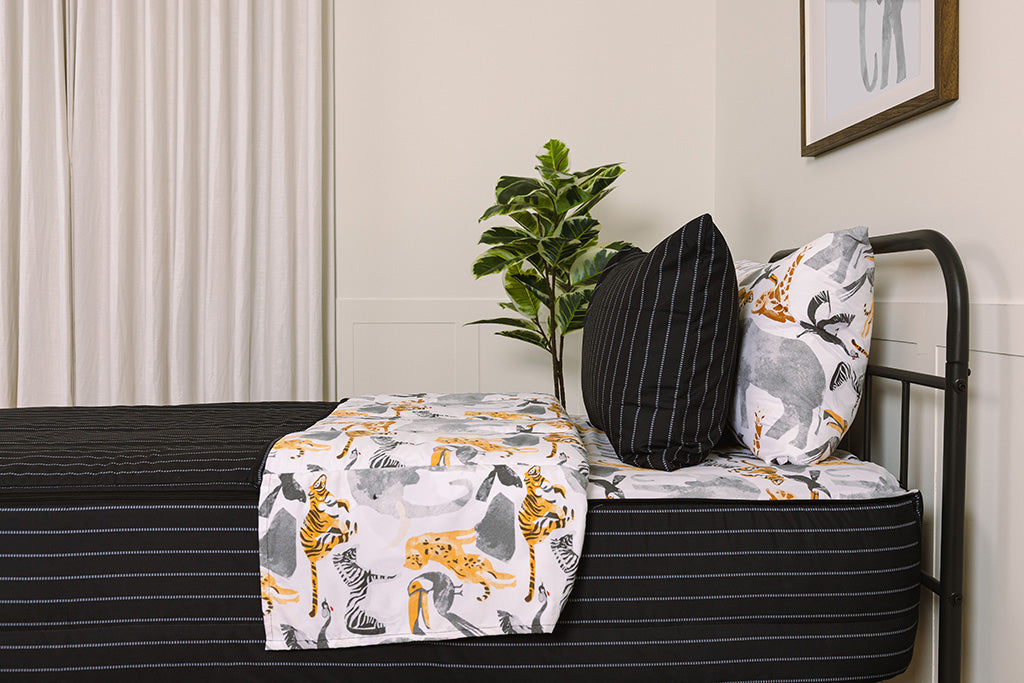 A bed made with jungle printed zipper bedding, showcasing the pillowcase and sham and the top of the bedding turned down to show the inside lining.