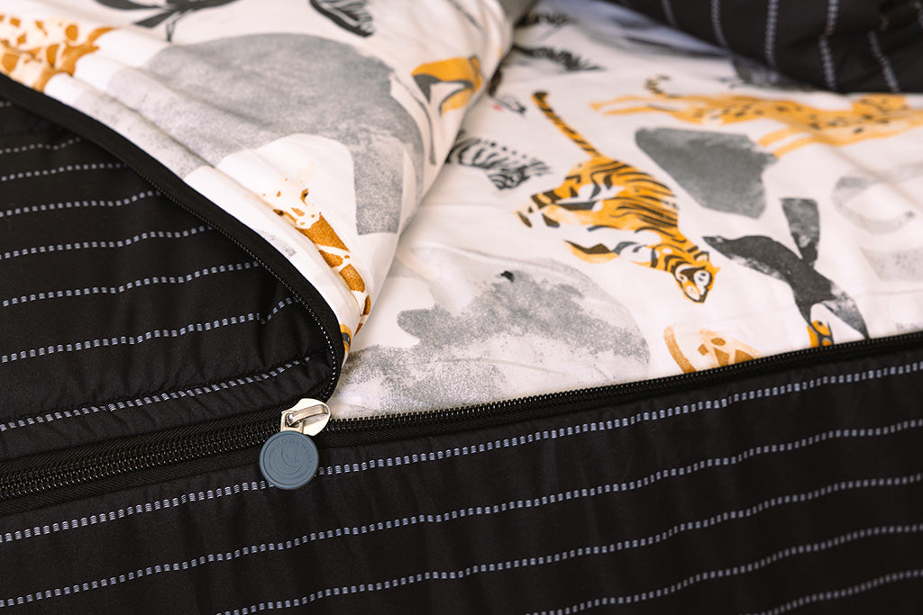 A tight shot of the zipper feature on a set of black and jungle animal printed zipper bedding.