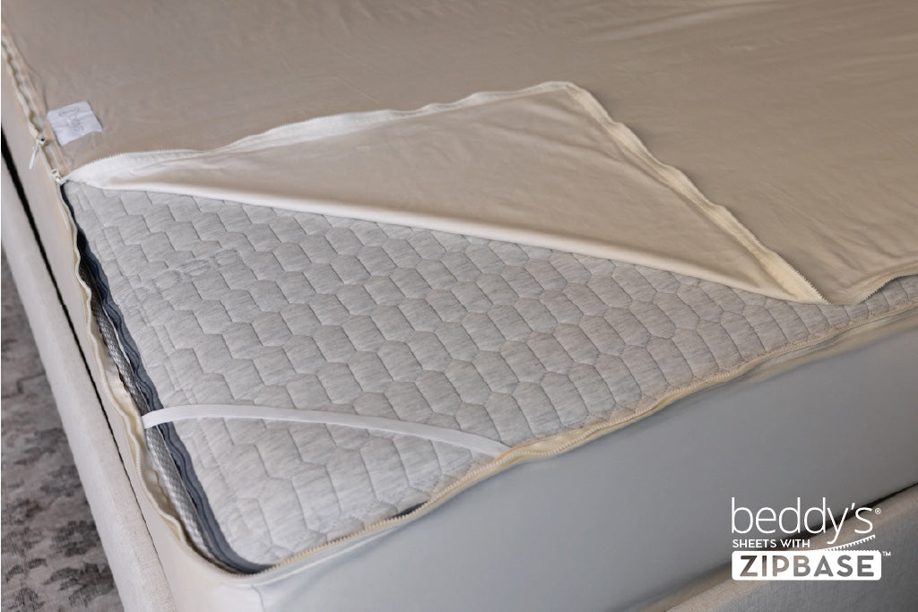 A zipper sheet unzipped on a corner of a mattress. 