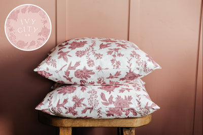 Two white floral pattern pillows stacked on a stool