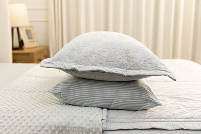 Light blue floral embossed zipper bedding with the sham and matching pillowcase stacked on top of each other in the middle of the bed.
