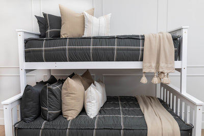 A bunk bed where both bunks are made with black plaid zipper bedding and an assortment of neutral bedding accessories