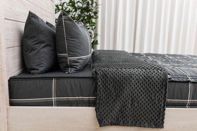 A close up of a bed made with black plaid zipper bedding, the top unzipped and pulled back to showcase the minky lining