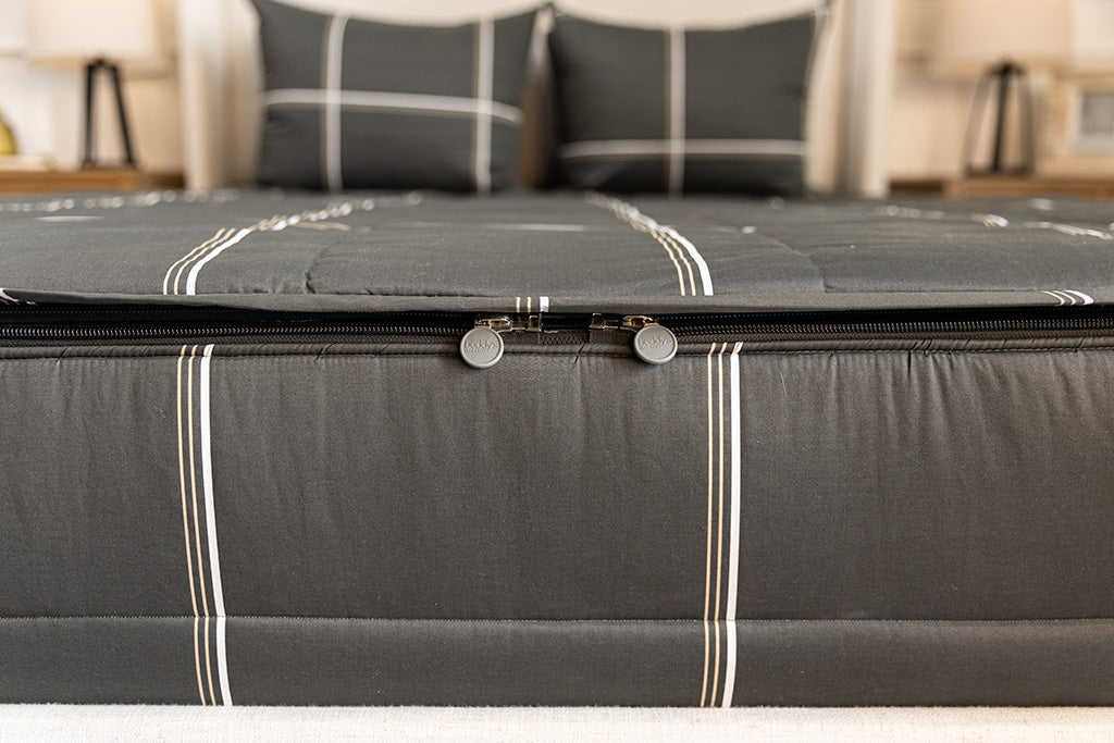 End of bed showing double zippers on charcoal plaid zipper bedding.