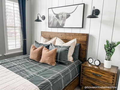 A bed made with black plaid zipper bedding and an assortment of neutral bedding accessories.