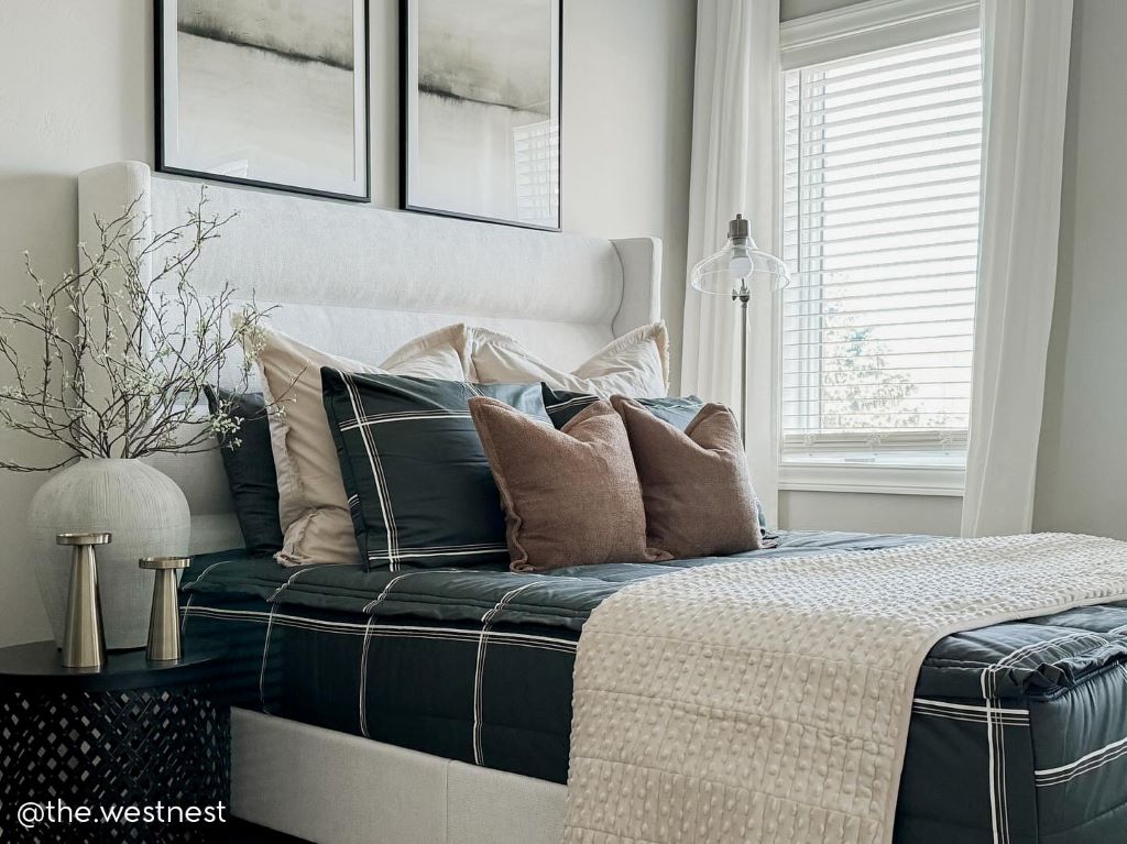 A queen bed made with black plaid zipper bedding and an assortment of neutral bedding accessories