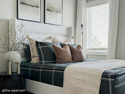 A queen bed made with black plaid zipper bedding and an assortment of neutral bedding accessories