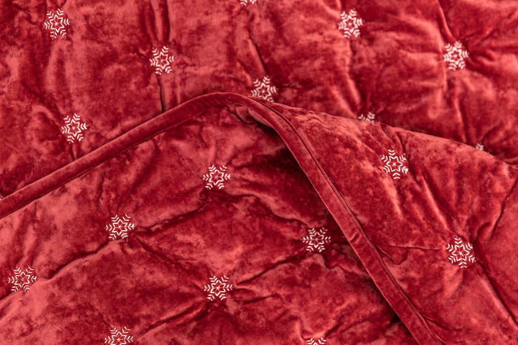Folded red blanket with white snowflakes.