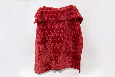 Person holding a red blanket with white snowflakes on a white background.
