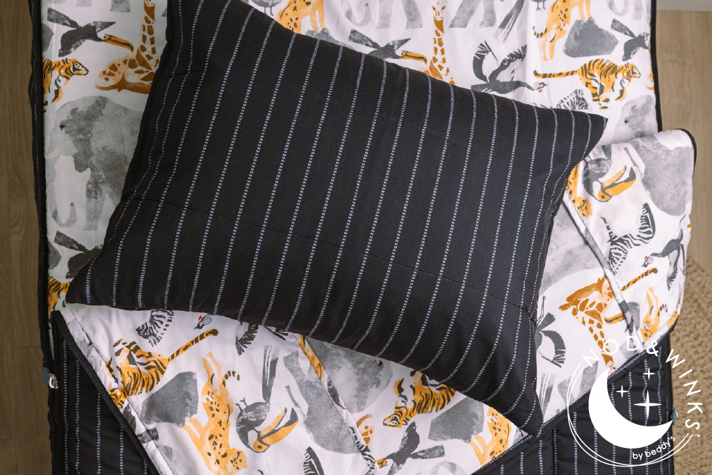 Black and jungle printed kids zipper bedding with the top unzipped and one side pulled back to reveal the inside lining, the pillow tossed on top of the bed.
