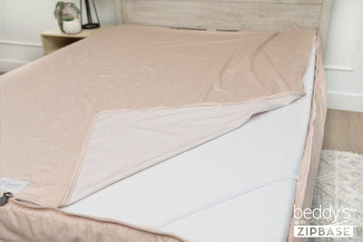 A ZipBase sheet partially unzipped and pulled back to show how it detaches from the rest of the base sheet wrapped around the sides of the mattress.