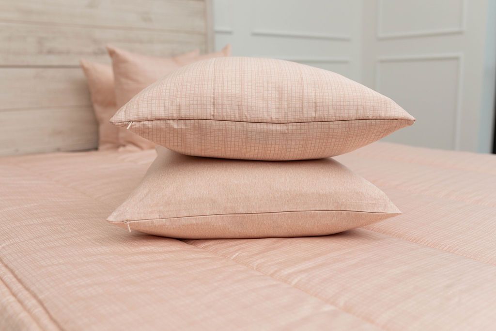 A peach sketched pattern pillowcase and matching sham on a made bed with peach zipper bedding. 
