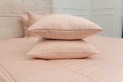 A peach sketched pattern pillowcase and matching sham on a made bed with peach zipper bedding. 