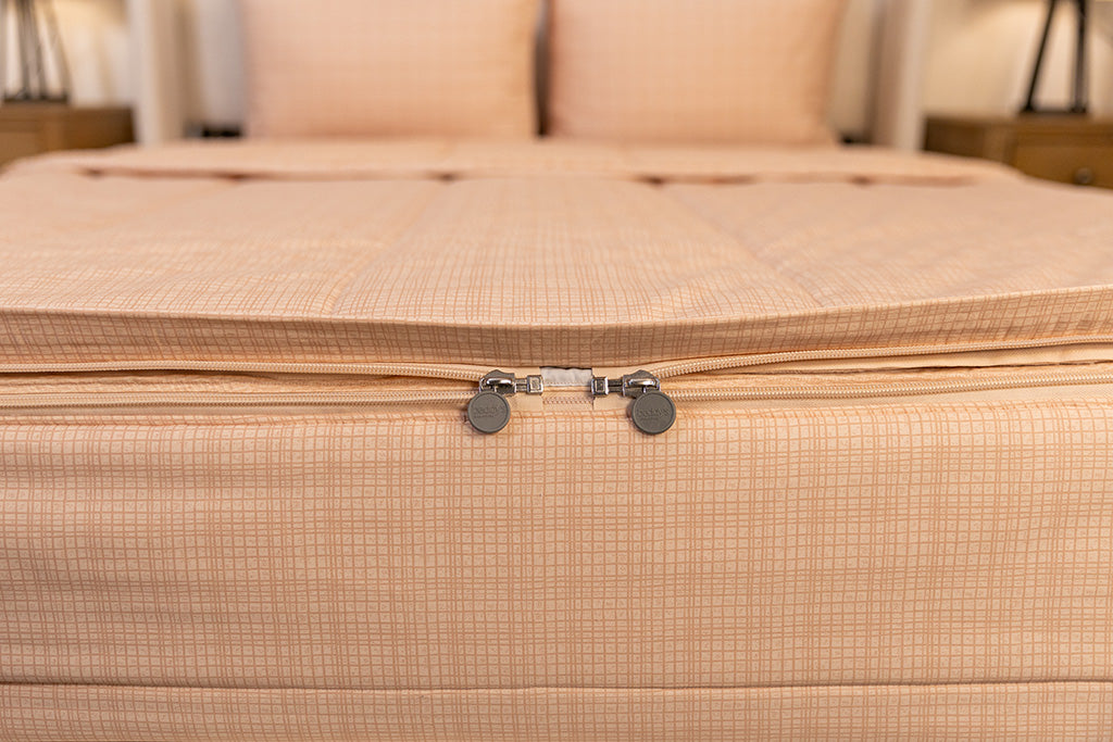 End of bed showing double zippers on light peach pink plaid zipper bedding.