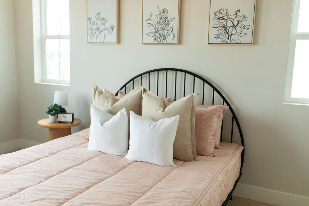 A bed made with peach pink zipper bedding and adorned neutral pillows.