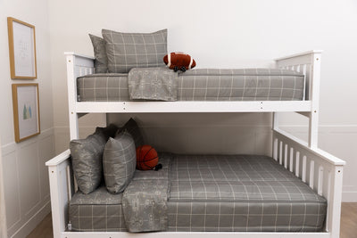 A bunk bed with the top twin and bottom full made with gaming printed zipper bedding and stuffed football and basketball on the beds. 