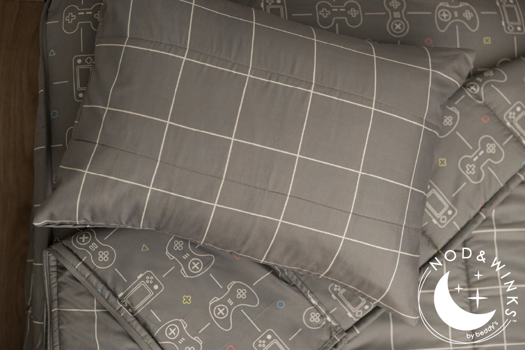 Gaming printed kids zipper bedding with the top unzipped and one side pulled back to reveal the inside lining, the pillow tossed on top of the bed.