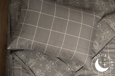 Gaming printed kids zipper bedding with the top unzipped and one side pulled back to reveal the inside lining, the pillow tossed on top of the bed.