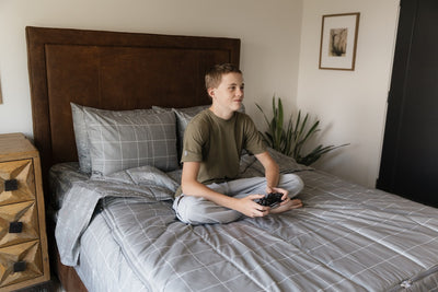 A teenager sitting on a queen size gamer zipper bedding. 