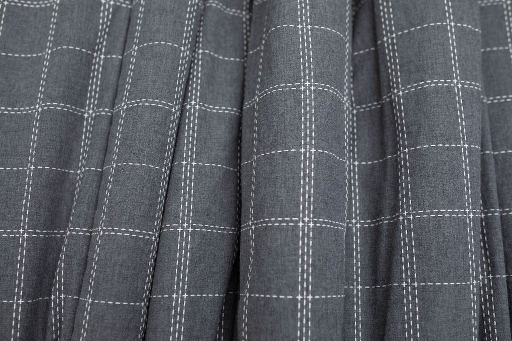 A close up of a deep gray and white grid stitching pattern blanket.