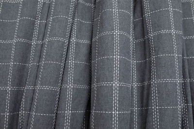 A close up of a deep gray and white grid stitching pattern blanket.