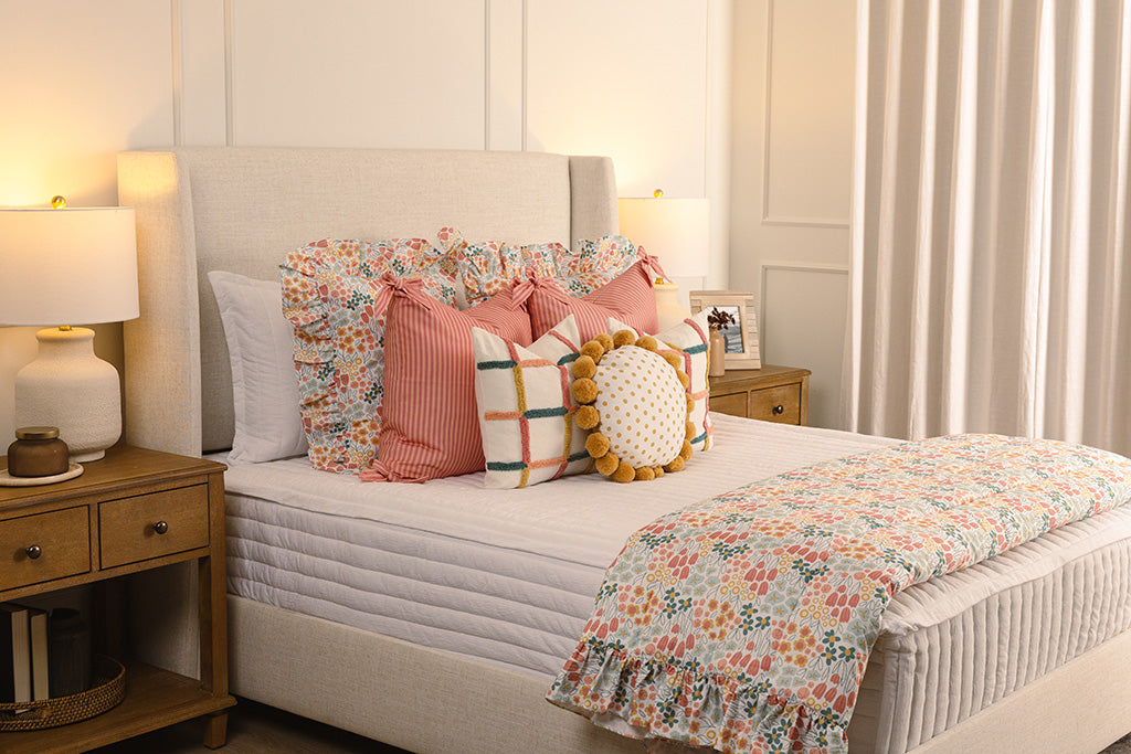 White quilted zipper bedding with multi-color and floral accessories on a queen bed.