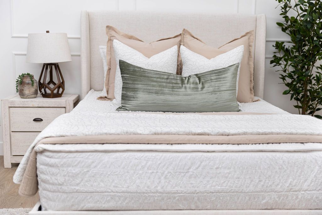 A bed made with white seersucker zipper bedding and neutral throw pillows and blankets