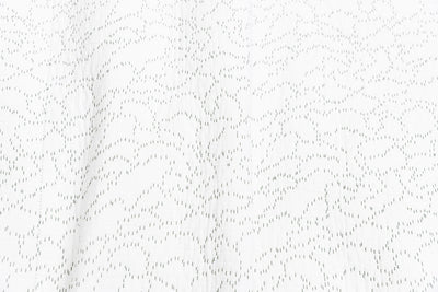 Close up of the white blanket with green stitching