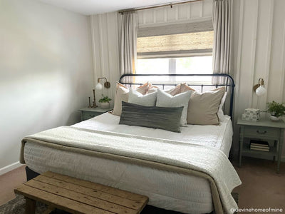 a bed made with seersucker white zipper bedding and an array of green and tan throw pillows and blankets.