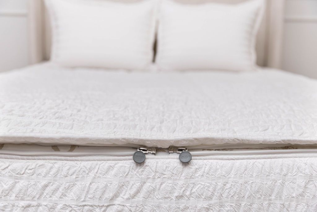 The foot of a bed made with seersucker white zipper bedding showing where the two zippers are located.
